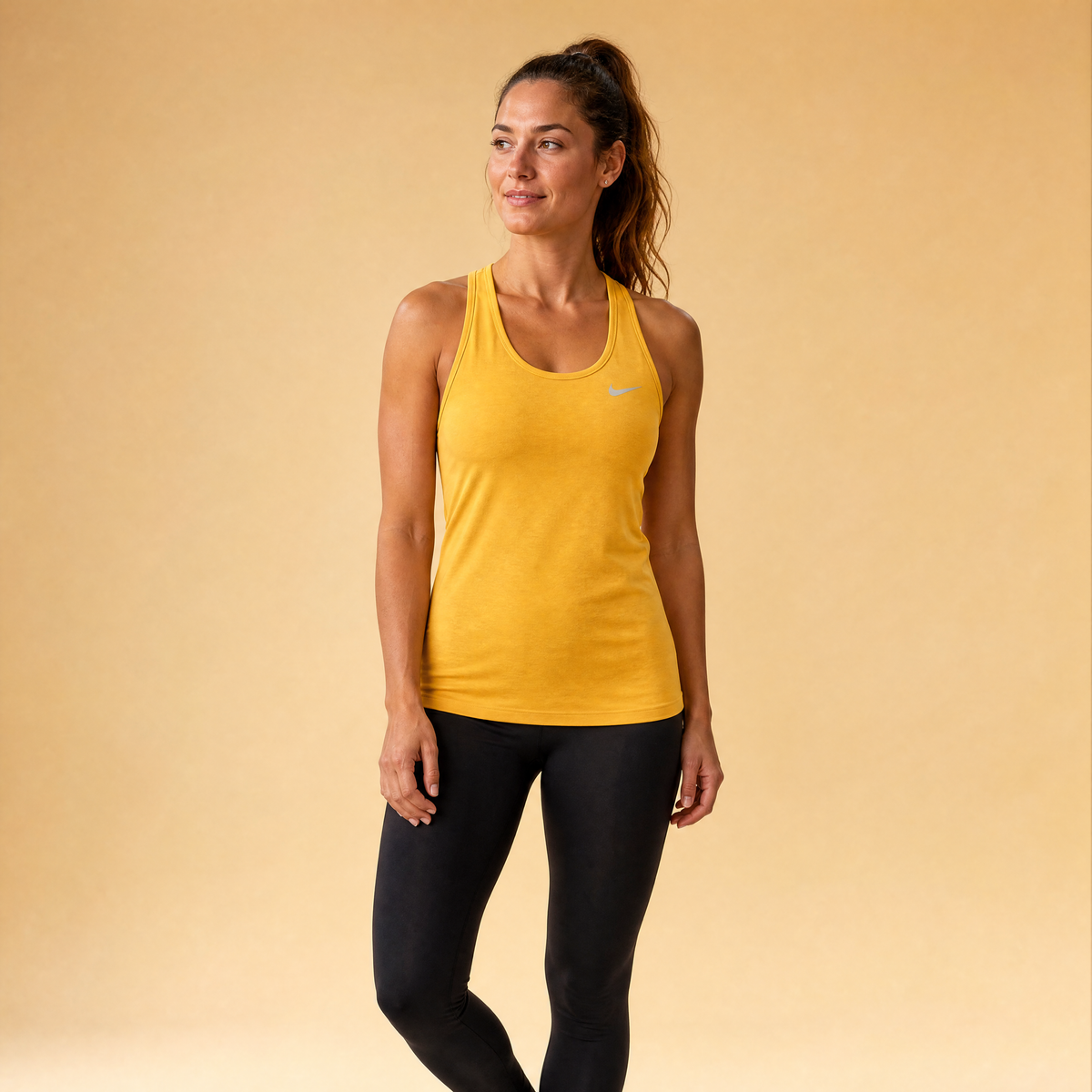 Female athlete modeling the yellow Nike Women's Yoga Layer Tank